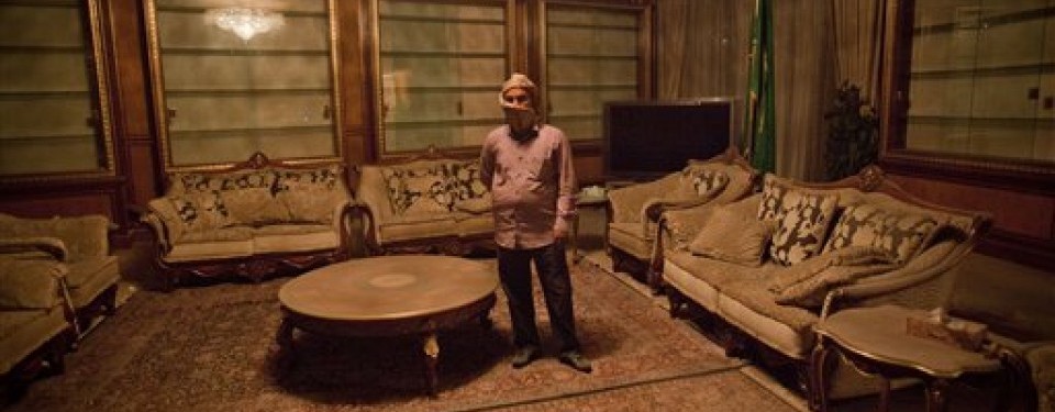 Seorang staf berdiri di ruang pertemuan di kompleks kediaman Qaddafi yang rusak akibat serangan NATO pada Senin (25/4).