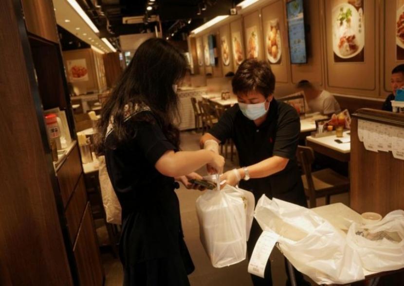 Hong Kong Banjir Sampah Plastik. Seorang staf restoran di Hong Kong melayani pelanggan di restoran yang membungkus makanan dengan kemasan plastik, 20 Juli 2020.