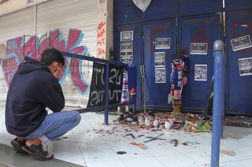 Seorang suporter Arema FC (Aremania) berdoa di depan pintu tribun 12 Stadion Kanjuruhan, Malang, Jawa Timur. LPSK menjamin terhadap perlindungan korban tragedi Kanjuruhan.