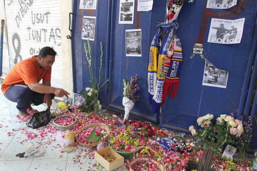 Seorang suporter Arema FC (Aremania) menaburkan bunga di depan pintu tribun 13 Stadion Kanjuruhan, Malang, Jawa Timur, Selasa (4/10/2022). 