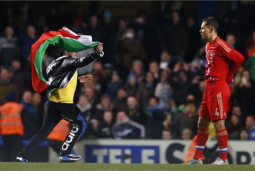 Seorang suporter (kiri) berlari masuk lapangan sambil membawa bendera saat Brasil menghadapi Rusia di laga persahabatan di Stadion Stamford Bridge, London, Senin (25/3). 