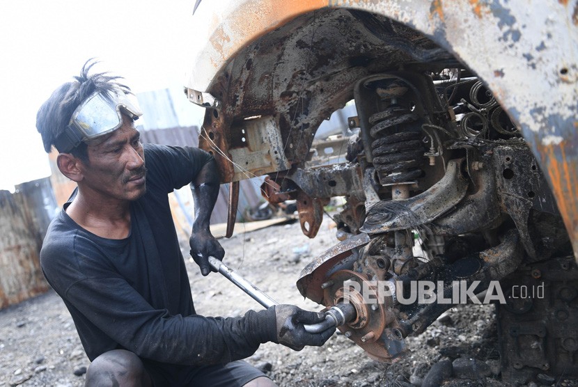 Seorang teknisi berusaha melepas onderdil yang masih bisa digunakan dari mobil yang hangus terbakar pasca unjuk rasa yang berujung anarkis di Jalan Trans Papua Pikhe, Wamena, Kabupaten Jayawijaya, Papua, Rabu (9/10/2019). 