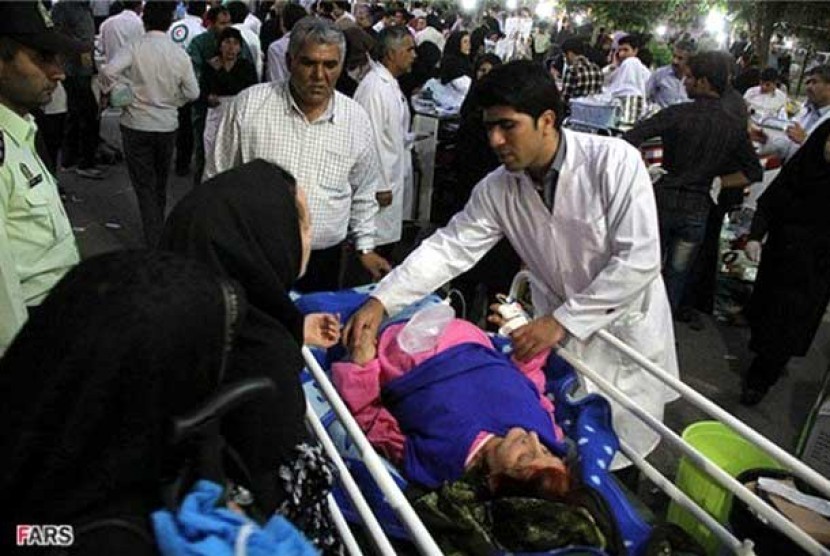 Seorang tenaga medis memeriksa korban luka akibat gempa di Ahar, Iran, pada Sabtu (11/8). 