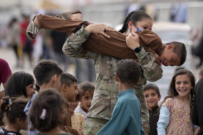 Seorang tentara AS bermain dengan anak-anak Afghanistan yang baru dievakuasi di Pangkalan Udara AS Ramstein, Jerman, Selasa, 24 Agustus 2021. Komunitas militer Amerika terbesar di luar negeri menampung ribuan pengungsi Afghanistan di kota tenda yang semakin padat. 