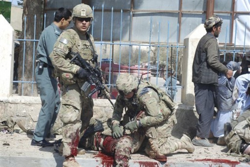 Seorang tentara AS memeriksa rekannya yang terkena ledakan bom bunuh diri di Kota Maimanah, Faryab, Afghanistan, Rab (4/4).