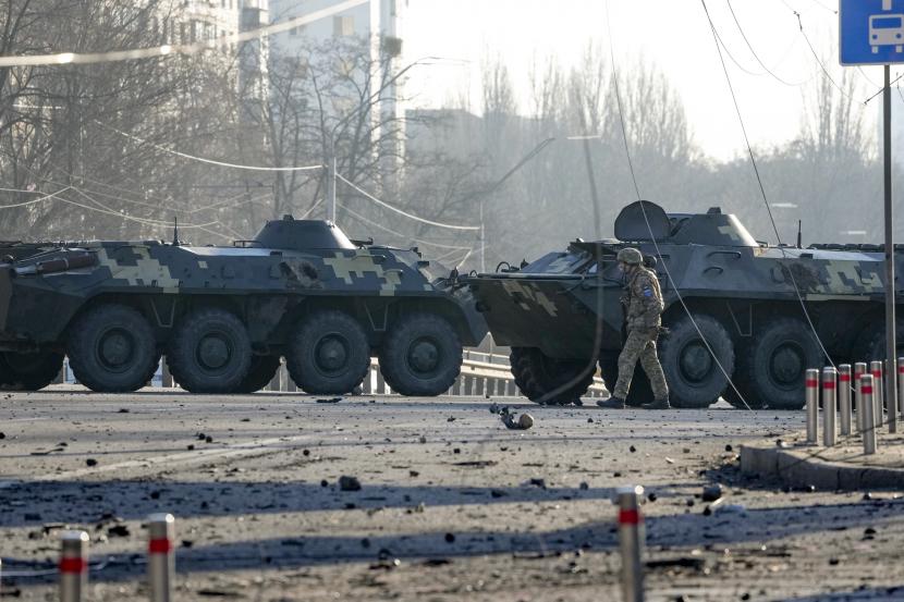 Seorang tentara berjalan di sepanjang kendaraan lapis baja Ukraina yang menghalangi jalan di Kyiv, Ukraina, Sabtu, 26 Februari 2022. 