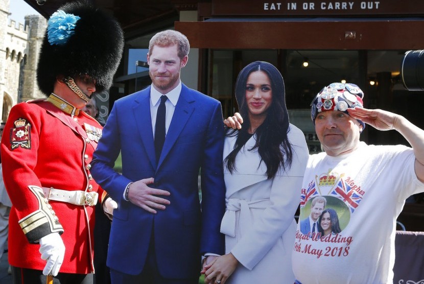 Seorang tentara melihat turis yang berfoto dengan patung karton Pangeran Harry dan Meghan Markle di Windsor, Inggris, (15/5).