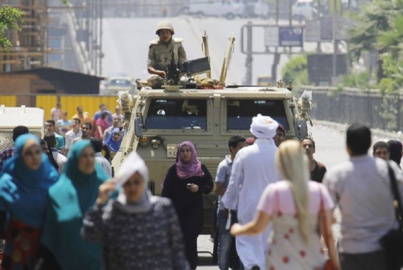 Seorang tentara Mesir berjaga dengan kendaraan lapis baja dekat lapangan Nahda, tempat para pendukung Presiden Muhammad Mursi berkemah di sekitar Universitas Kairo, Giza 