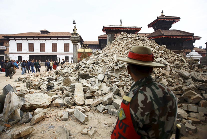  Seorang tentara Nepal berdiri di depan sebuah bangunan kuil yang hancur akibat gempa di Kathmandu, Nepal, Ahad (26/4). (Reuters/Navesh Chitrakar)