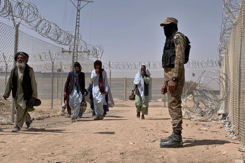 Seorang tentara Pakistan berjaga-jaga ketika orang-orang Afghanistan masuk ke Pakistan melalui titik penyeberangan perbatasan, di Chaman, Pakistan, Jumat, 20 Agustus 2021.