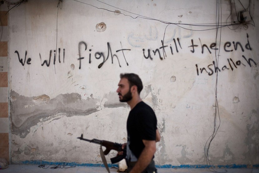   Seorang Tentara Pembebasan Suriah berjalan melalui sebuah jalan di distrik Amariya di Aleppo, Suriah, Senin (10/9).    (Manu Brabo/AP)