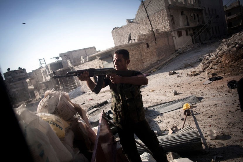   Seorang Tentara Pembebasan Suriah dalam posisi menembak di sebuah jalan di distrik Amariya Aleppo, Suriah, Senin (10/9).    (Manu Brabo/AP)