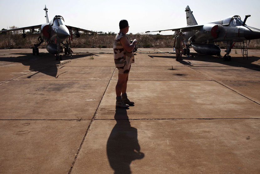  Seorang tentara Perancis berdiri di antara dua jet tempur Mirage F1 di pangkalan udara militer Mali di Bamako, Senin (14/1). (Reuters/Joe Penney)