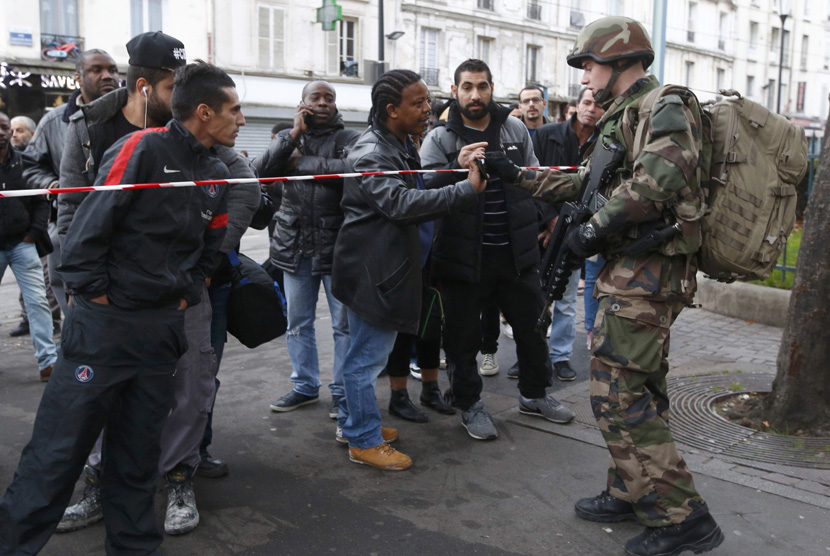 A French soldier checks the identity papers of a man in the area where shots were exchanged in Saint-Denis, France, near Paris, November 18, 2015. (Reuters/Jacky Naegelen)