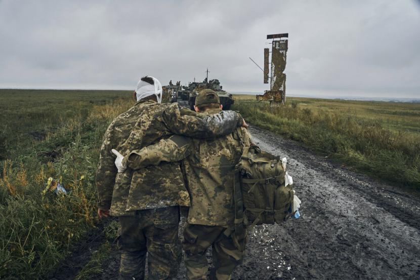 Seorang tentara Ukraina membantu sesama prajurit yang terluka di jalan di wilayah yang dibebaskan di wilayah Kharkiv, Ukraina