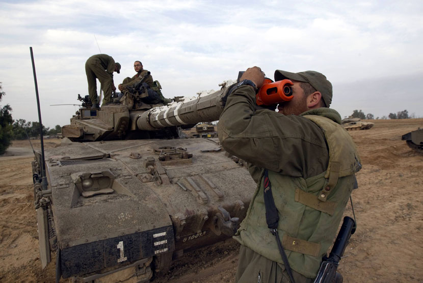 Seorang tentara Zionis Israel memeriksa laras tank di dekat perbatasan dengan Jalur Gaza, Sabtu (17/11). (Reuters/Ronen Zvulun)