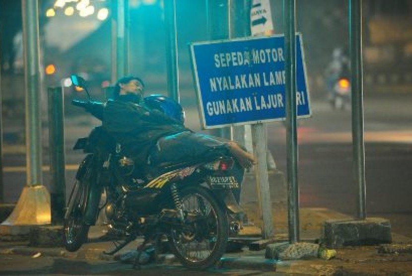 Seorang tukang ojek terlelap di atas sepeda motornya di lampu lalulintas Jl Gatot Subroto - Kuningan, Jakarta