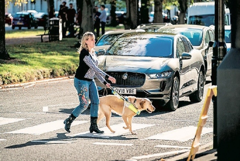 Seorang tuna netra menyeberang jalan dengan bantuan anjing. Jaguar mengembangkan sistem peringatan bagi tuna netra pejalan kaki. Sistem itu akan disematkan di kendaraan listrik mereka