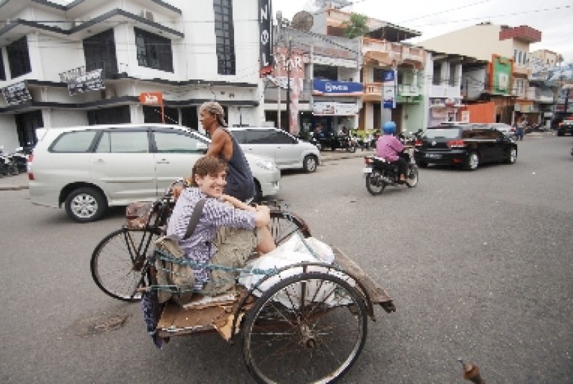 Seorang turis Belanda menaiki becak berkeliling kota tua Padang, Sumatra Barat, Senin (1/12).