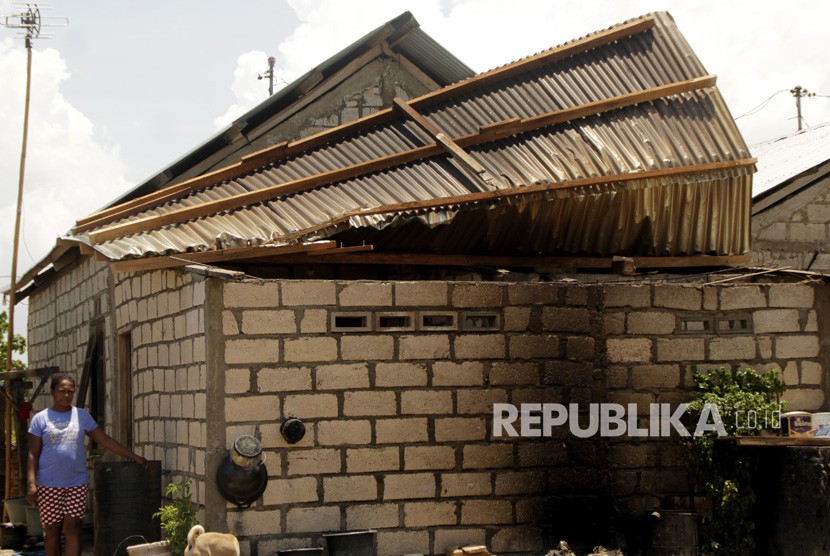 Seorang wanita berdiri di samping rumahnya yang atapnya hampir rubuh diterjang oleh angin di Kota Kupang, NTT.
