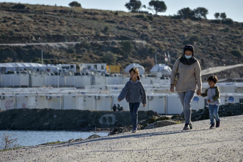 Seorang wanita berjalan dengan anak-anak di kamp pengungsi Karatepe, di pulau Lesbos, Aegean timur laut, Yunani, Kamis, 25 November 2021.
