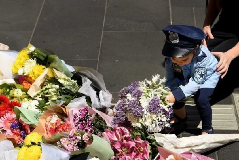 Seorang wanita dan anak-anak meletakan bunga di monumen di Bourke Street bagi para korban amukan sebuah kendaraan.