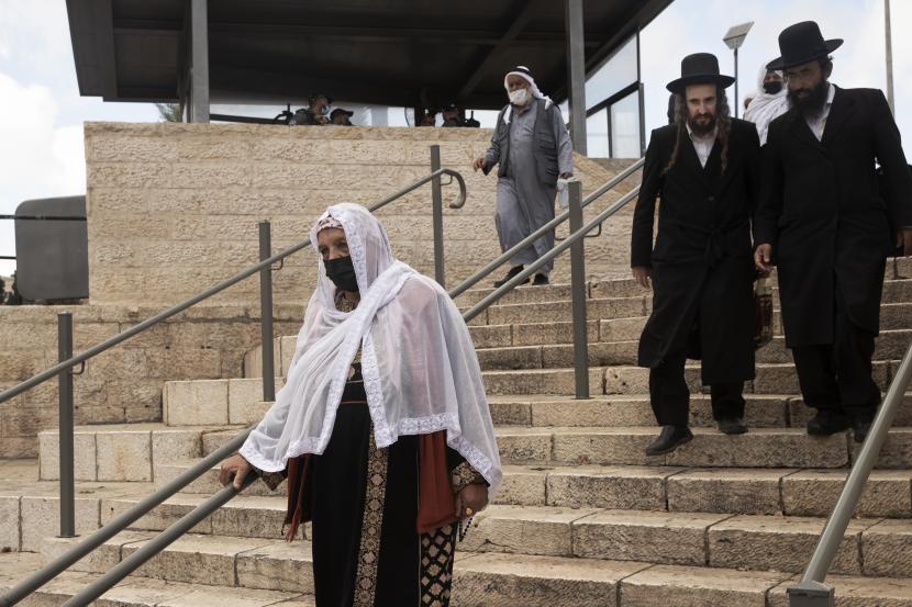 Seorang wanita dengan pakaian tradisional Palestina berjalan menuju Gerbang Damaskus ke Kota Tua Yerusalem untuk sholat di kompleks Masjid Al Aqsa yang menandai Maulid al-Nabi, hari kelahiran Nabi Muhammad, Selasa, 19 Oktober 2021. 