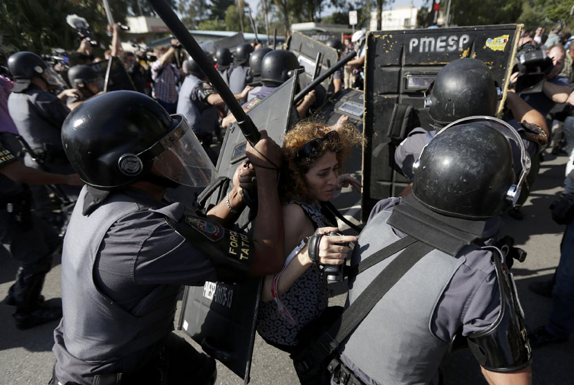 Seorang wanita didorong polisi antihuru-hara dalam bentrokan dengan demonstran yang memprotes Piala Dunia 2014 di Sao Paulo, Brasil, Kamis (12/6). 