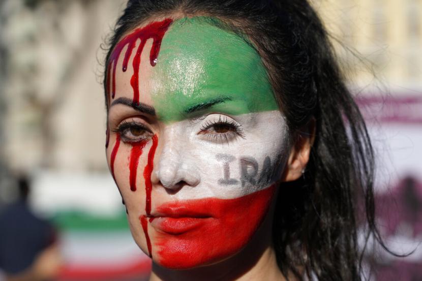 Seorang wanita dilukis di wajahnya saat memprotes kematian Mahsa Amini, seorang wanita yang meninggal saat dalam tahanan polisi di Iran, selama rapat umum di Roma tengah, Sabtu, 29 Oktober 2022.