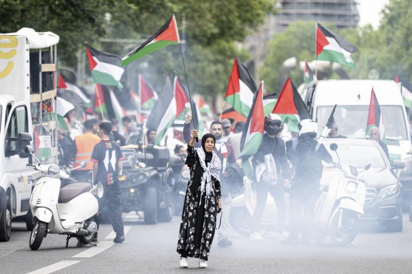 Seorang wanita melambaikan bendera Palestina di depan iring-iringan mobil pro-Palestina di Berlin, Jumat, 2 Agustus 2024. Seorang pemudi keturunan Jerman-Iran diputus bersalah oleh Pengadilan Berlin karena melaungkan semboyan pro-Palestina from the river to the sea dalam sebuah demonstrasi tahun lalu. 