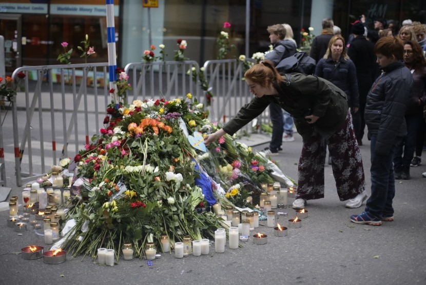 Seorang wanita meletakkan karangan bunga di depan sebuah toko di Ahlens, Sabtu (8/4). Aksi ini sebagai bentuk simpati atas peristiwa terorisme di Stockholm. 