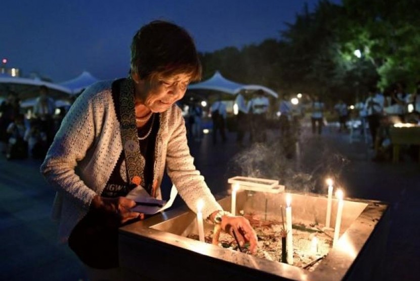 Seorang wanita meletakkan lilin di Peace Memorial Park Hiroshima, saat peringatan 71 tahun bom nuklir dijatuhkan di Kota Hiroshima