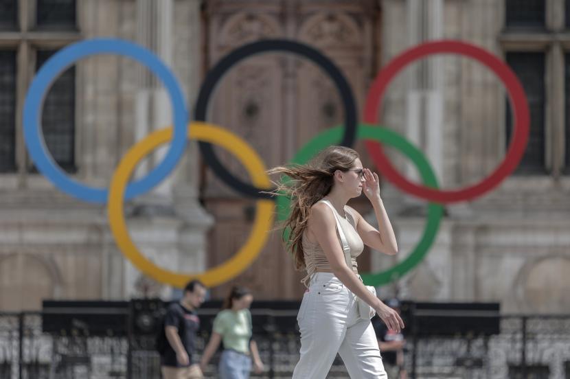 Seorang wanita melewati cincin Olimpiade di Balai Kota di Paris.