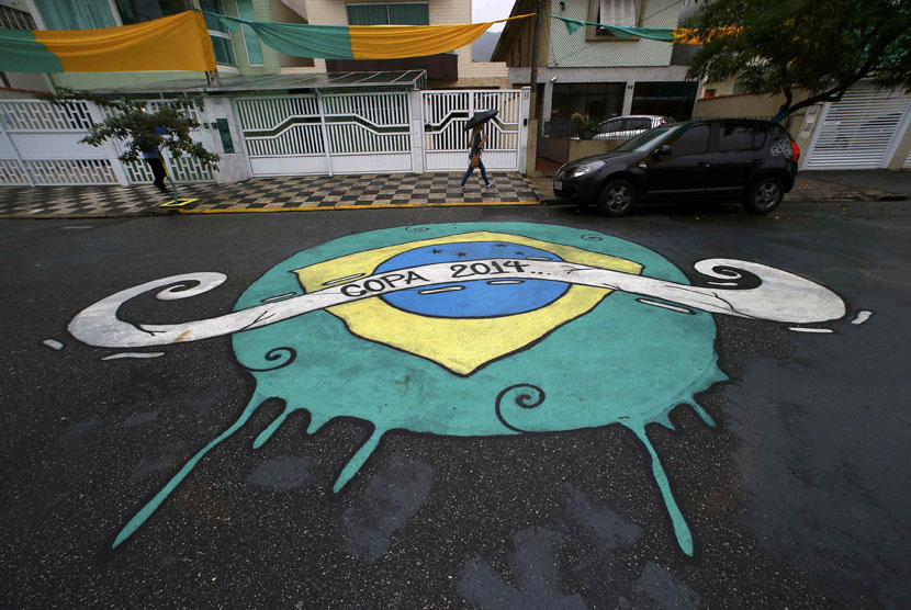 Seorang wanita melewati grafiti yang dibuat di jalan untuk menyambut Piala Dunia 2014 Brasil. 