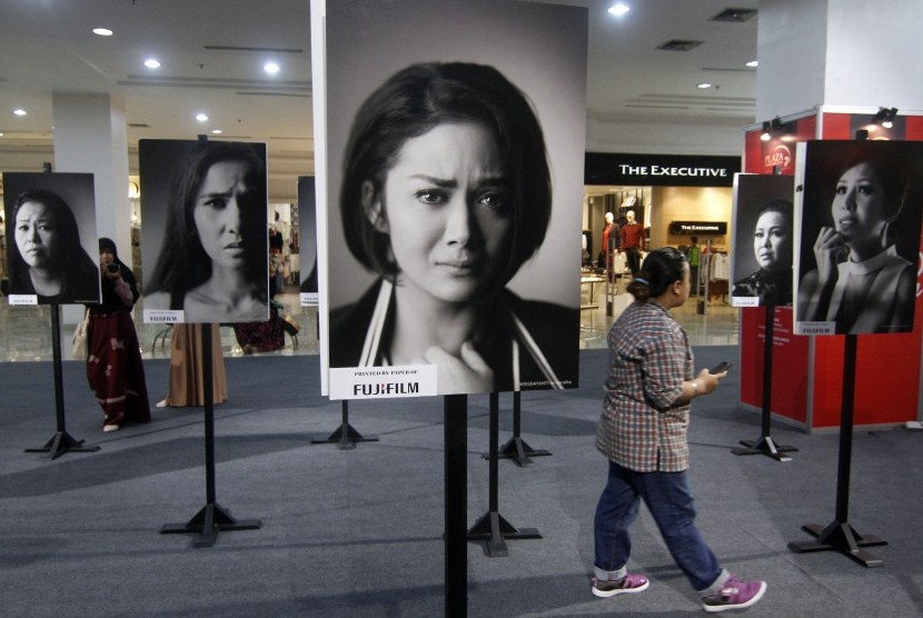  Seorang wanita melintas diantara foto-foto potret puluhan artis perempuan Indonesia dengan tema kampanye 