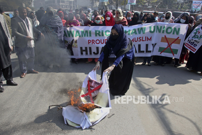 Seorang wanita membakar patung Perdana Menteri India Narendra Modi sementara dia bersama yang lain mengambil bagian dalam demonstrasi yang diselenggarakan oleh Awami Rickshaw Union untuk memprotes larangan gadis Muslim mengenakan jilbab di kelas di beberapa sekolah, di negara bagian Karnataka, India selatan, di Lahore , Pakistan, Kamis, 10 Februari 2022.