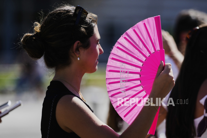 Seorang wanita memegang kipas tangan di tengah panasnya cuaca di Berlin, Jerman, Rabu, 2 Juli 2025.