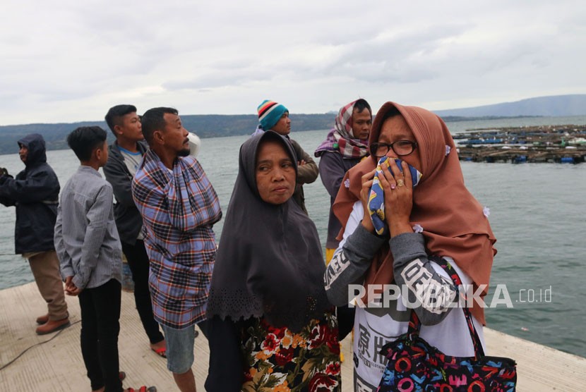 Seorang wanita mencium baju anaknya, penumpang KM Sinar Bangun, yang tenggelam di Danau Toba, Simalungun, Sumatra Utara, Selasa (19/6).