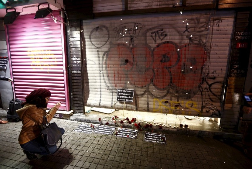 Seorang wanita mengambil gambar karangan bunga serta kartu yang diletakkan di tempat bom bunuh diri terjadi di Istanbul, Turki, pada Sabtu (19/3).