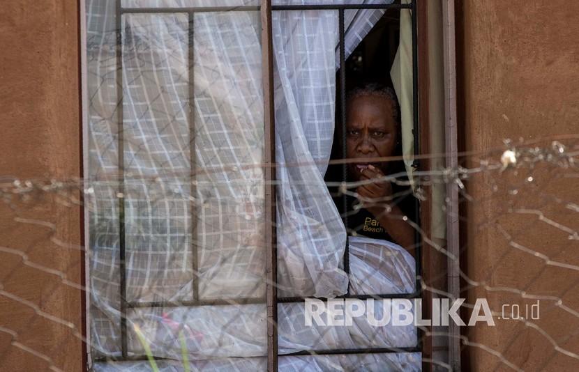 Seorang wanita mengawasi melalui jendela ketika anggota Pasukan Pertahanan Nasional Afrika Selatan berpatroli di jalan di pemukiman informal Diepsloot, utara Johannesburg, Afrika Selatan, Kamis (16/4). Presiden Afrika Cyril Ramaphosa memperpanjang lockdown dengan tambahan dua minggu sebagai upaya berkelanjutan untuk menahan penyebaran COVID-19. 