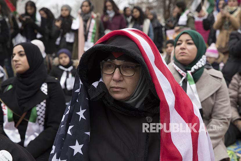 Seorang wanita mengenakan bendera Amerika di atas kerudungnya pada aksi menentang kebijakan Trump atas Yerusalem di President Park tidak jauh dari istana kepresidenan Gedung Putih Washington, DC, Jumat (8/12) waktu setempat, atau (9/12) dini hari WIB. 