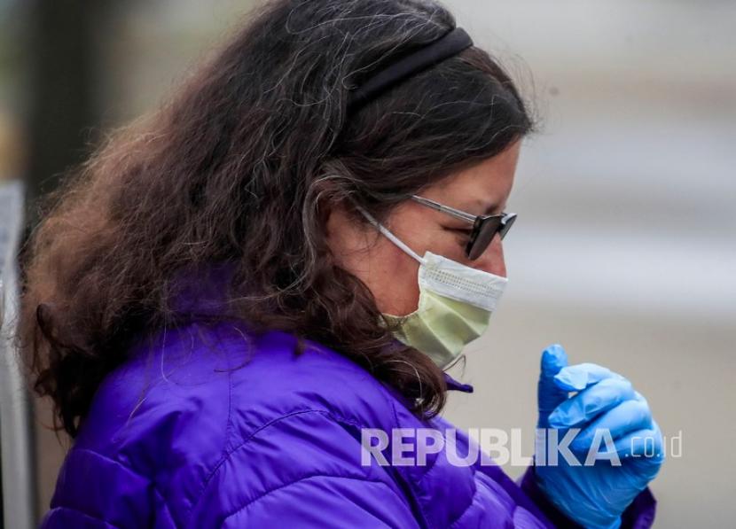 Seorang wanita mengenakan masker dan sarung tangan pelindung di halte bus Community First Medical Center, Chicago, Illinois, AS, Senin (30/3). Penelitian menunjukkan RNA virus ada di udara tempat pasien terinfeksi berada. 