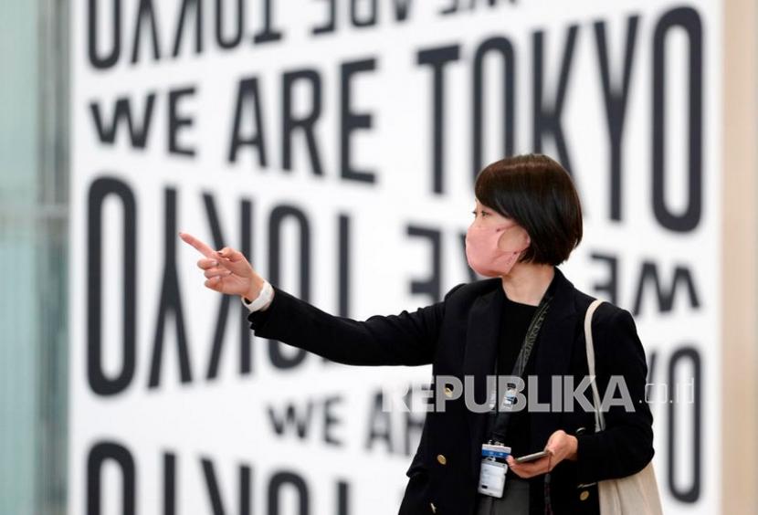  Seorang wanita mengenakan masker pelindung berjalan di depan papan di Bandara Internasional Haneda di Tokyo, Jepang. Jepang kemungkinan besar menghadapi gelombang kedelapan infeksi Covid-19. Ilustrasi.