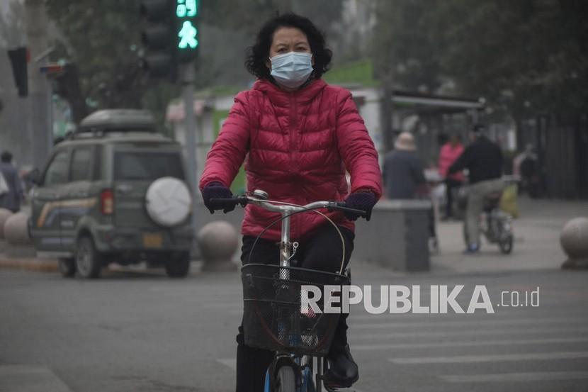  Seorang wanita mengenakan masker pelindung mengendarai sepeda selama pandemi coronavirus di Beijing, Cina, 05 November 2021. Kurang dari 24 jam setelah ditemukan kasus pertama, otoritas kesehatan di China menemukan kasus kedua Covid-19 varian Omicron pada Selasa (14/12/2021). 
