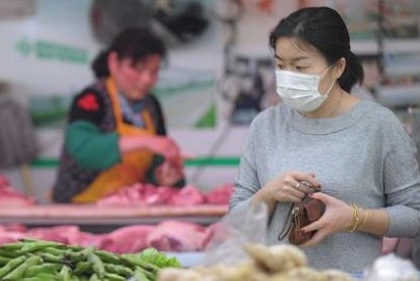 Seorang wanita mengenakan masker saat berbelanja di sebuah pasar di Shanghai.