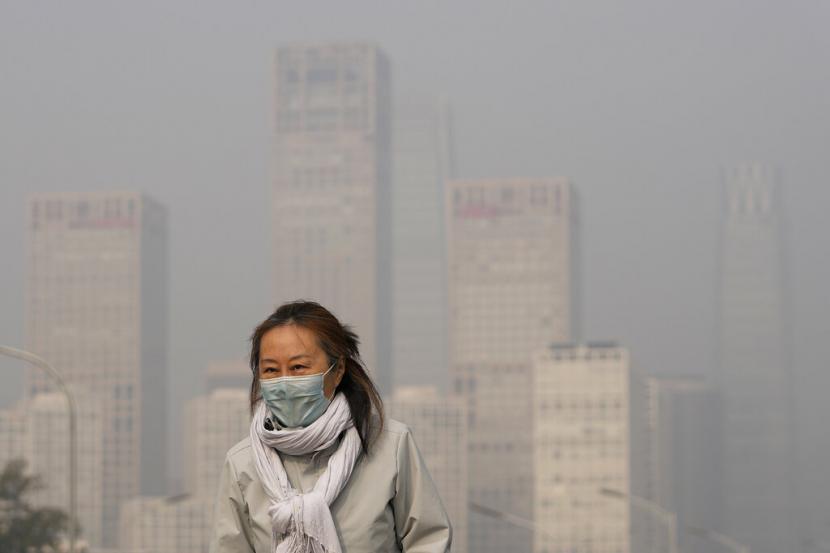 Seorang wanita mengenakan masker untuk melindungi diri dari COVID-19 berjalan di depan gedung perkantoran di Kawasan Pusat Bisnis yang diselimuti kabut polusi di Beijing, Kamis, 18 November 2021. Beijing menerapkan kebijakan pencegahan dan pengendalian Covid-19 dengan memperketat impor. Ilustrasi.