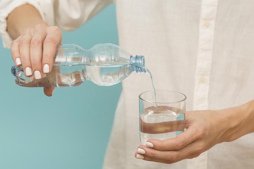 Seorang wanita menuang air minum ke dalam gelas (ilustrasi). Bolehkah minum dari gelas yang sama dengan yang bukan mahram?