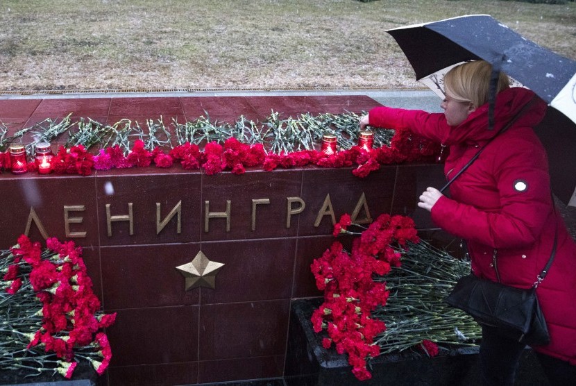 Seorang wanita menyalakan lilin mengenang korban ledakan di kereta bawah tanah St Petersburg di memorial bertuliskan Leningrad atau dikenal dengan St Peterburgs di Moskow, (3/4).