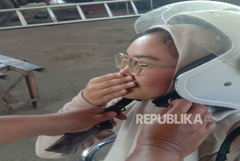 Seorang wanita muda mendatangi Markas Damkar Kabupaten Indramayu untuk meminta tolong melepaskan helmnya yang sulit dilepas karena tali pengikat yang terlalu kuat, Kamis (10/7/2025). 