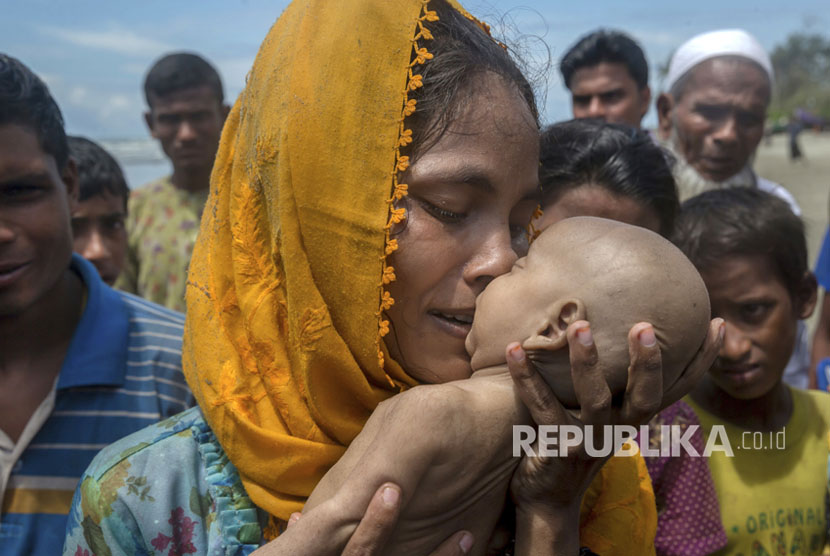 Seorang wanita Muslim Rohingya Hanida Begum, yang menyeberang dari Myanmar ke Bangladesh, mencium anak bayinya Abdul Masood yang meninggal saat kapal yang mereka tumpangi terbalik sebelum mencapai pantai Teluk Benggala, di Shah Porir Dwip, Bangladesh, Kamis  (14/9).